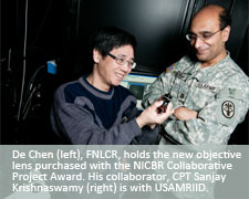 De Chen (left), FNLCR, holds the new objective lens purchased with the NICBR Collaborative Project Award. His collaborator, CPT Sanjay Krishnaswamy (right) is with USAMRIID.