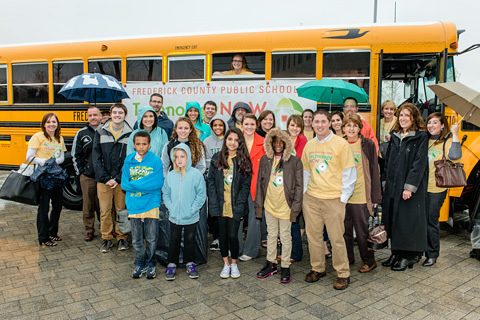 Tour group standing in front of a school bus.