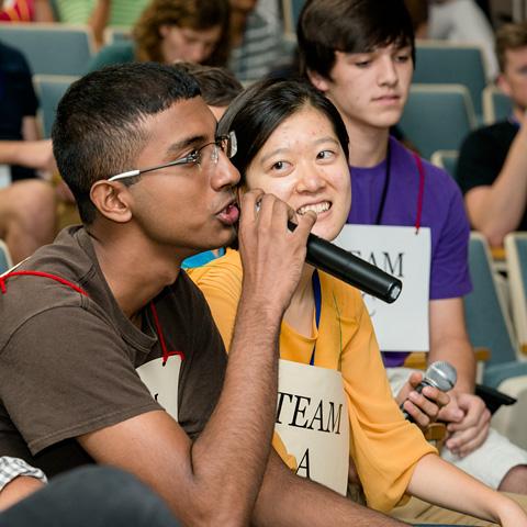 two students, one talking into a microphone.