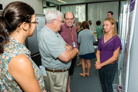 Two researchers and a student discussing a scientific poster.