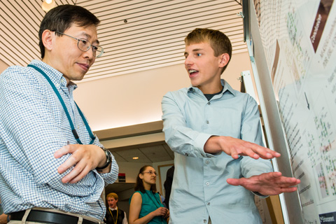 A researcher and a student discussing a scientific poster.