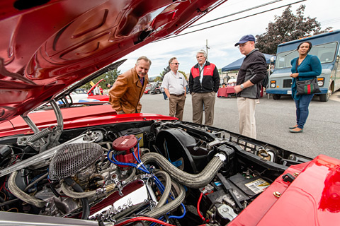 People looking under the hood of a car.
