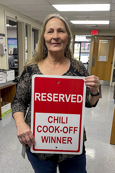 Dawn Goings, the 17th Chili Cook-off champion, poses with the sign for her reserved parking space. (Photo by Sarah Hooper.)