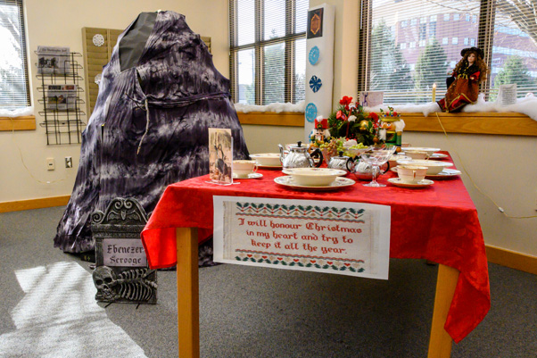 The Ghost of Christmas Yet to Come—a tower of books covered with paper and cloth—gestures to Ebenezer Scrooge’s grave in the Scientific Library (left), while the banquet of the Ghost of Christmas Present adorns an adjacent table (right)