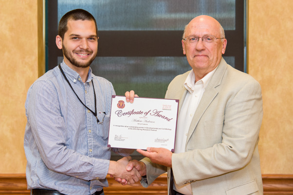 Matthew Anderson receives his award for Outstanding Presentation at the Scientific Symposium from NCI Associate Director Craig Reynolds, Ph.D.