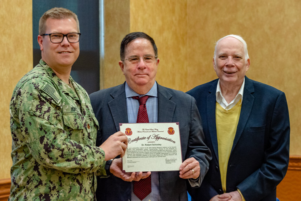 Robert “Chip” Schooley, M.D., (center) receives a certificate of appreciation from Lt. Cmdr. Robert Hontz, Ph.D., U.S. Naval Medical Research Center, (left) and retired Capt. Alfred Mateczun, M.D., U.S. Naval Medical Research Center, (right) for delivering the keynote address.