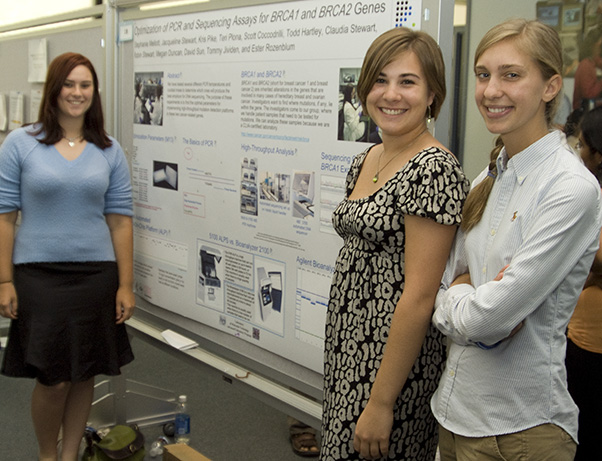 Jackie Stewart (left, background) as an intern at the 2008 Summer Student Poster Day. Pictured alongside her are fellow interns Stephanie Mellott (center; also now a Frederick National Laboratory employee) and Megan Duncan (right). (Photo from the SPGM archive)