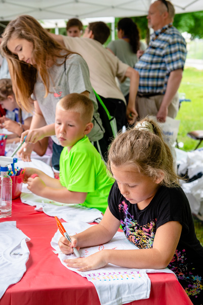 Children make tie-dye-style shirts at the “Art Through Science” table.