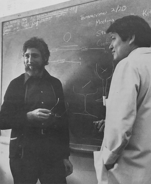 Dr. Michael Yarmolinsky (left) and Dr. Robert Yuan (right) work at a chalkboard. Both were senior scientists in the Cancer Biology Program. Photo likely taken in 1980. (1980 annual report)