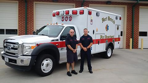 Two members of Company 50 pose with their ambulance.