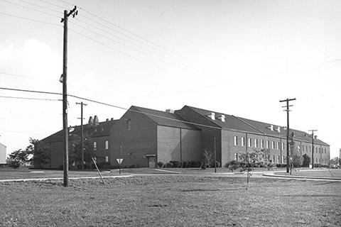 Black-and-white photograph of a large brick building seen from across a large lawn