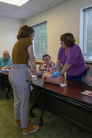 A participant practices on a training dummy while Emme Tissue instructs