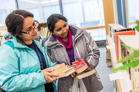 Two women browse books at the Book Swap