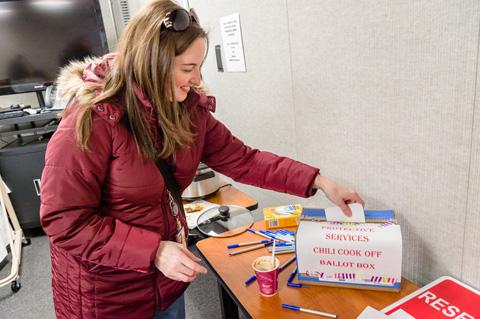 A visitor to the Protective Services chili cook off places her vote in the ballot box.