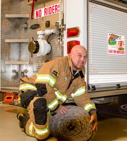 Fireman kneeling by truck.