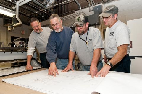 Four men viewing building plans.