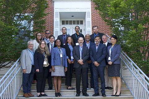 A group of men and women wearing business attire gathered for a photograph on the steps in front of a building