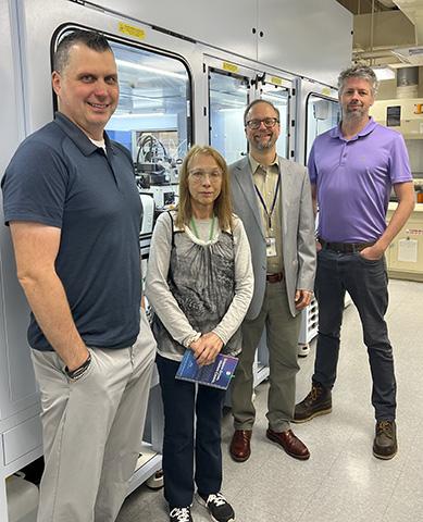 Four scientists standing in front of the NCI-60 robotic apparatus.