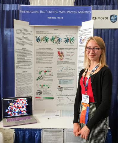 Student standing by her poster.