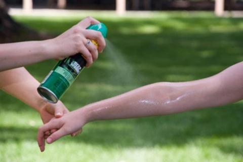 Two people applying insect repellent. 