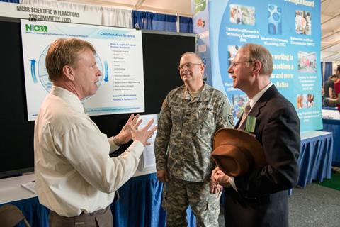 Three men discussing a poster.