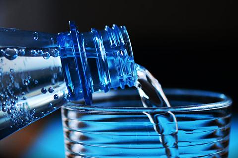 Image of bottled water being poured into drinking glass