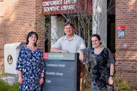 Three members of the Scientific Library staff stand outside of the building.