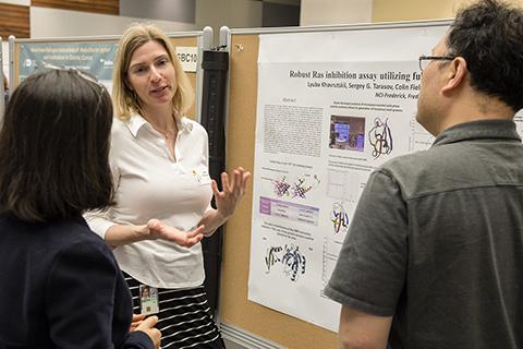 A researcher and visitors at the scientific poster display.