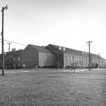 Black-and-white photograph of a large brick building seen from across a large lawn