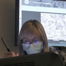 Photo of a woman drawing on a tablet, with a computer screen in the background
