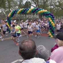 A crowd of runners passing under a balloon archway
