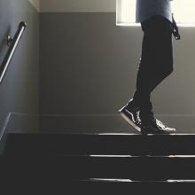 A person's legs shown walking up a fight of stairs