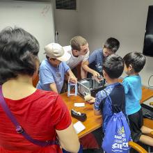 A group of kids and adults working on a computer
