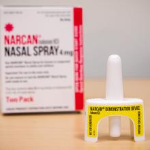 A nasal spray dose of NARCAN sits in front of its box