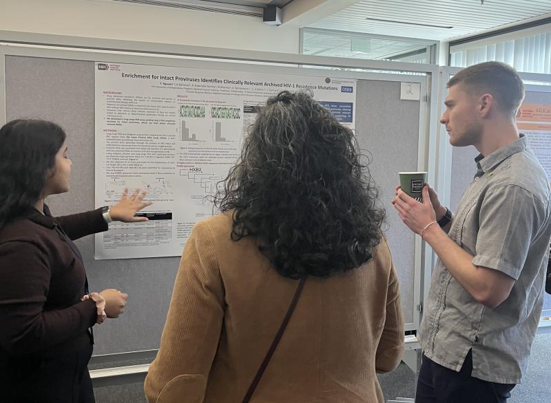 Postbac Krushnangi Das (left) explains her poster to Postbac Poster Day attendees, including her fellow postbac, Thomas Abney-Lidahl (right). 