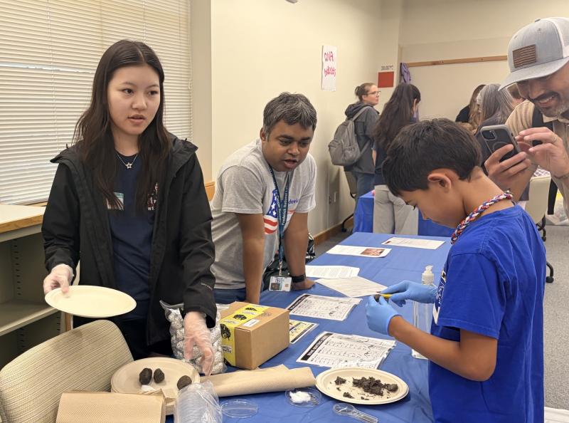 A child concentrates on his owl pellet dissection at one of the activity stations as his parent and volunteers look on. Image credit: Karolina Wilk