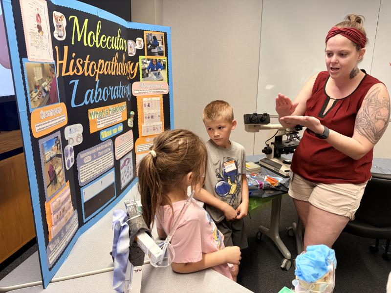 A volunteer explains some of the work at the Molecular Histopathology Laboratory to kids attending the event. Image credit: Karolina Wilk